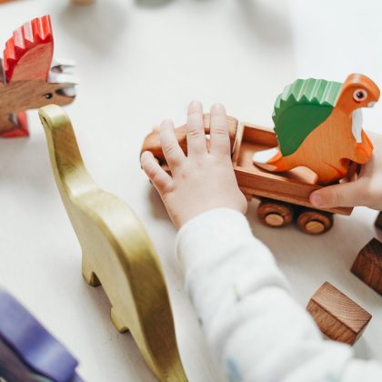 Manos de un bebé jugando con dinosaurios de madera
