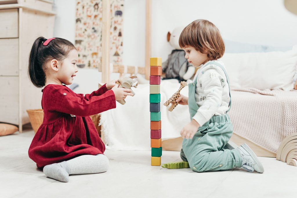 Niños jugando con una torre de bloques y unos animales de madera